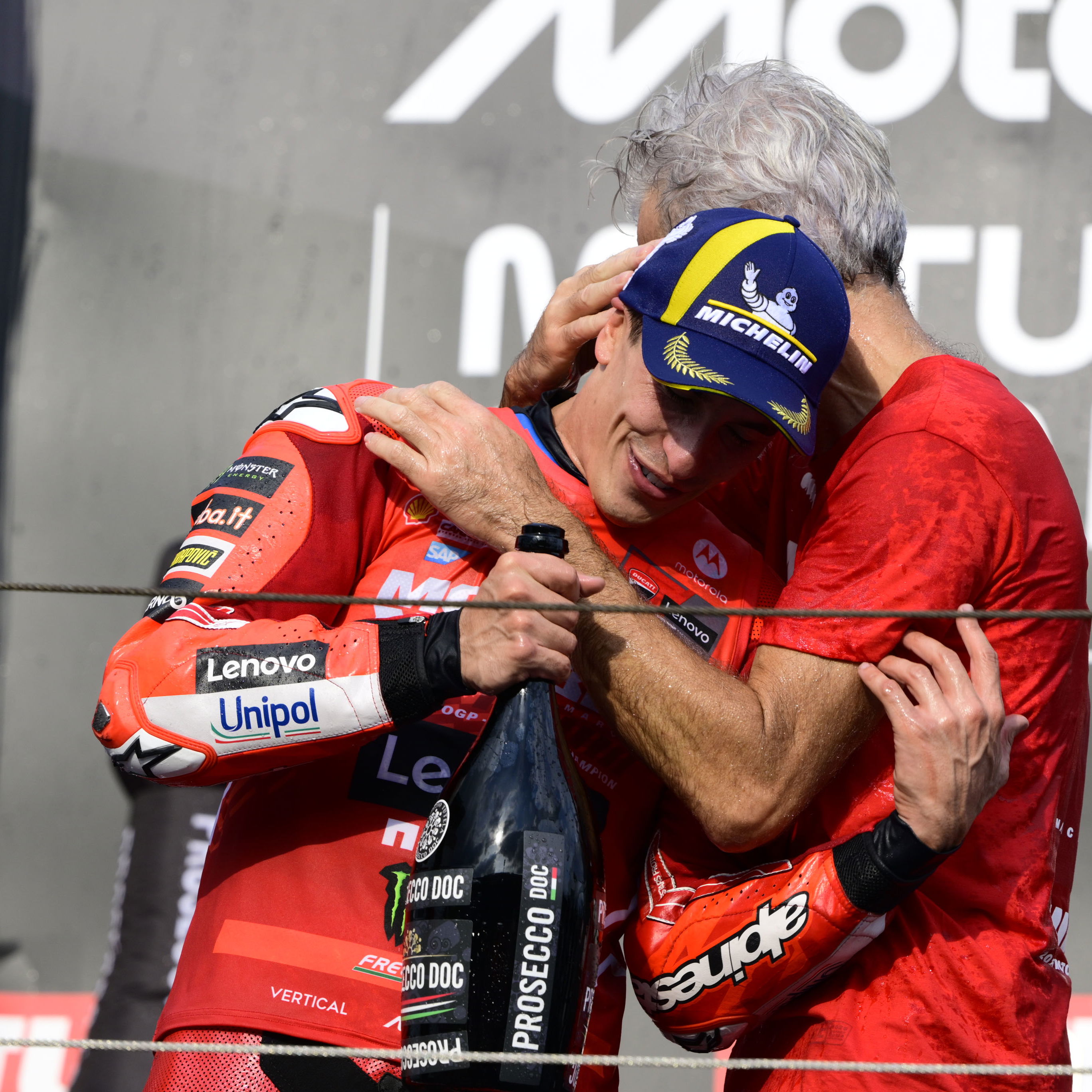 Marc Marquez, Gigi Dall'Igna embrace on 2025 MotoGP Japanese Grand Prix podium. Credit: Gold and Goose.
