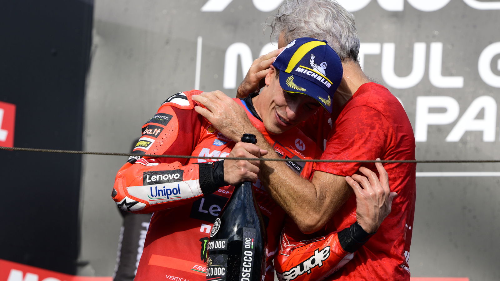 Marc Marquez, Gigi Dall'Igna embrace on 2025 MotoGP Japanese Grand Prix podium. Credit: Gold and Goose.