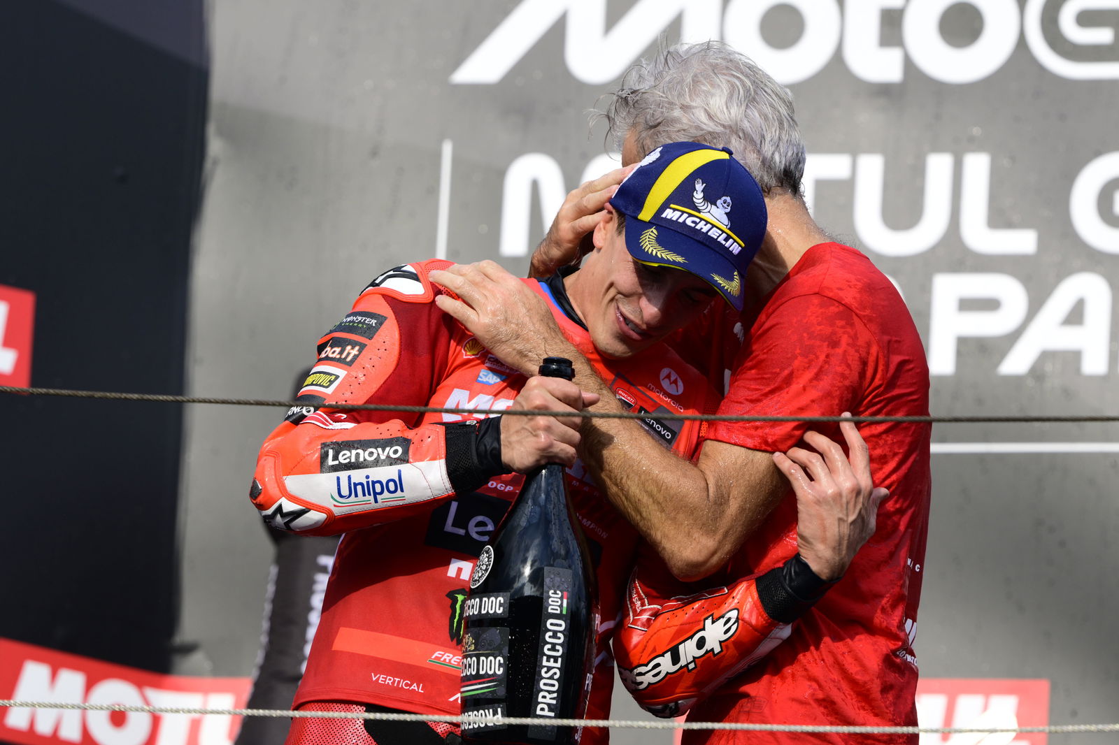 Marc Marquez, Gigi Dall'Igna embrace on 2025 MotoGP Japanese Grand Prix podium. Credit: Gold and Goose.