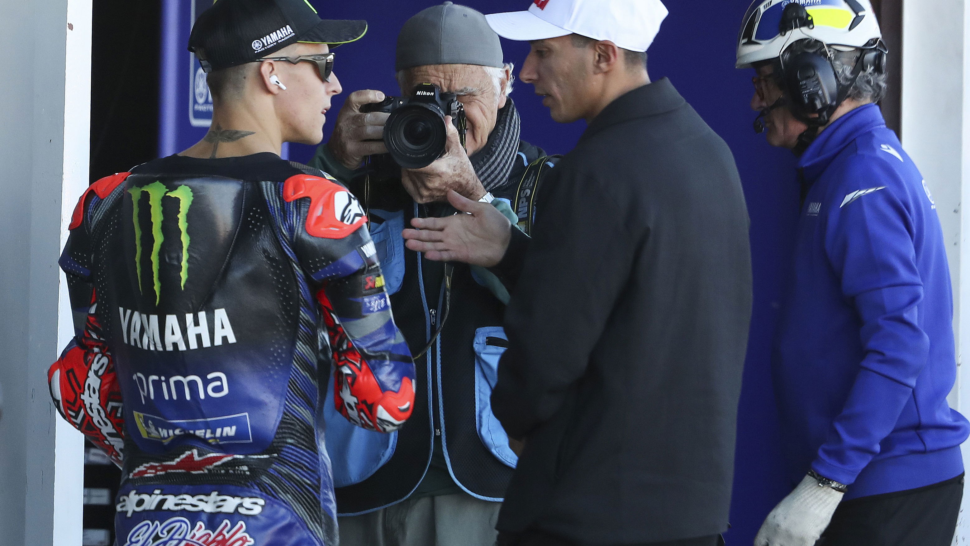 Fabio Quartararo speaks with Toprak Razgatlioglu, 2025 MotoGP Valencia Grand Prix, pit lane. Credit: Gold and Goose.