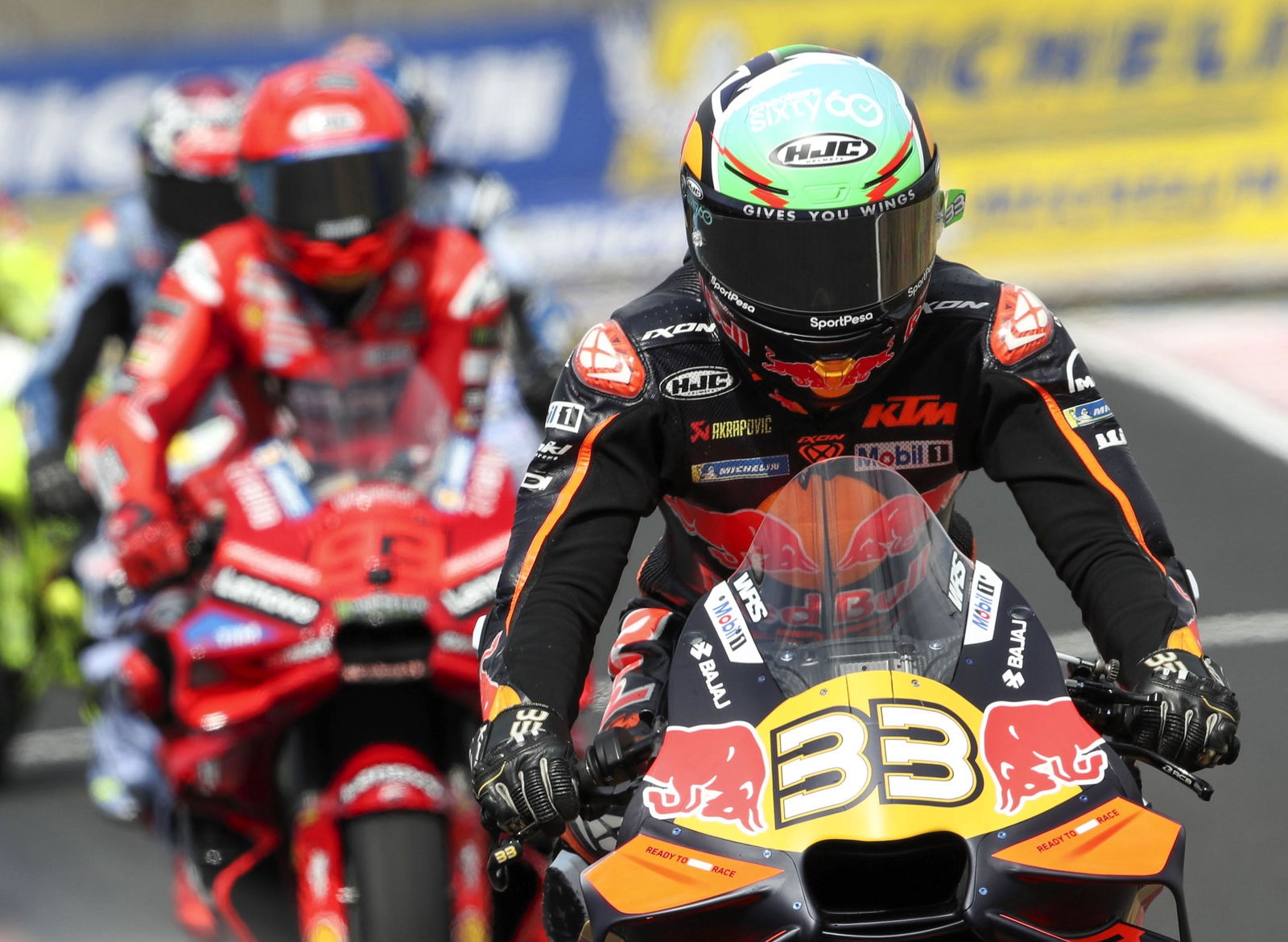 Brad Binder leads Marc Marquez out of the pits during MotoGP 2025.
