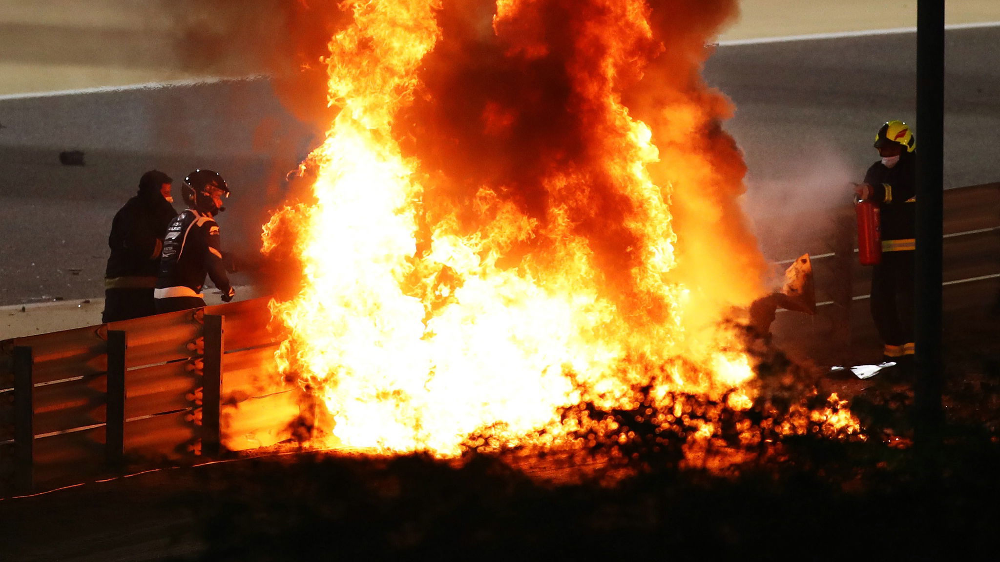Marshals put out the fire of Romain Grosjean (FRA) Haas F1 Team at the start of the race, with Dr Ian Roberts (GBR) FIA