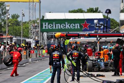 George Russell (GBR) Mercedes AMG F1 W14 makes a pit stop to fix damage as a Ferrari mechanic collects an errant wheel